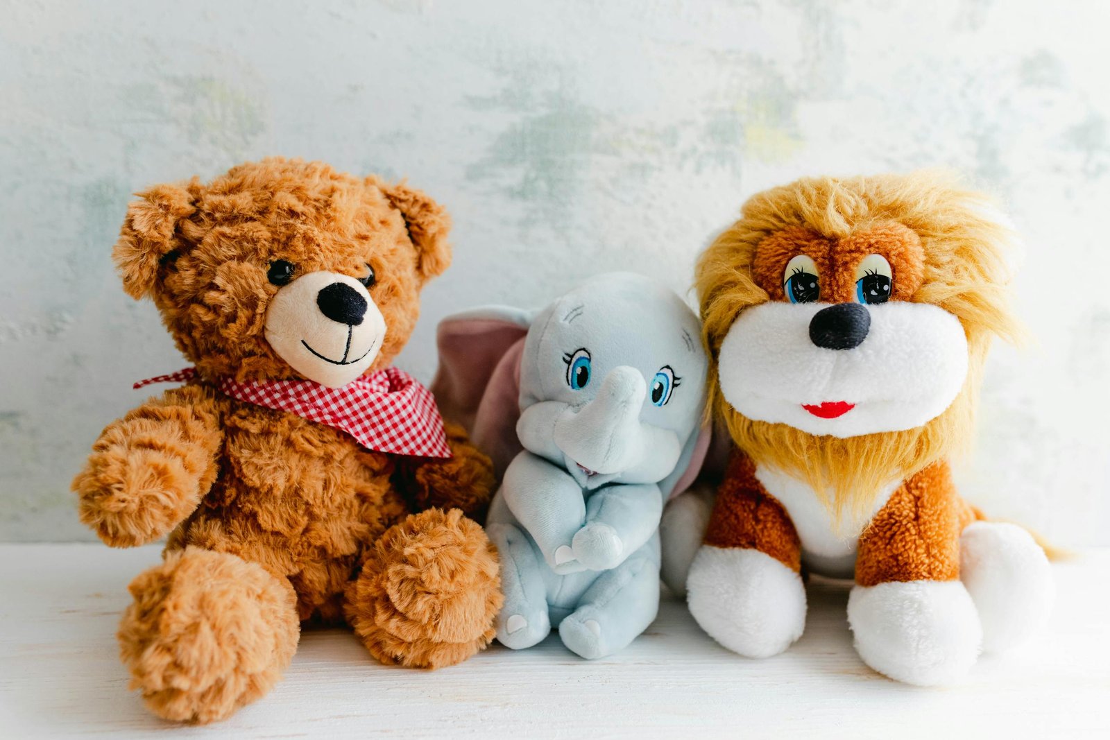 Adorable plush toys featuring a teddy bear, lion, and elephant perfect for children's gifts or decor.